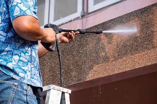 Someone Cleaning Concrete Wall Outside of Building